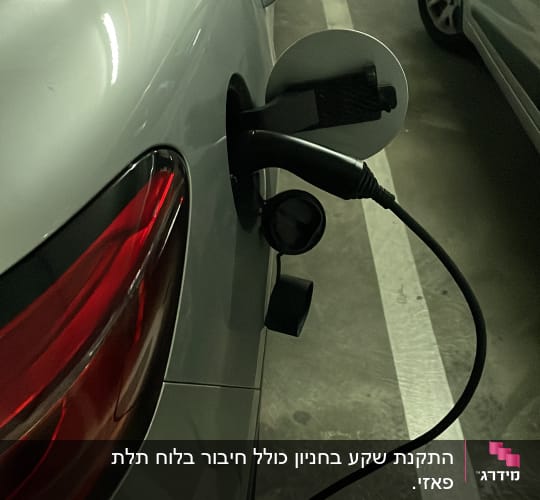 רכב חשמלי מחובר לכבל טעינה בחניון